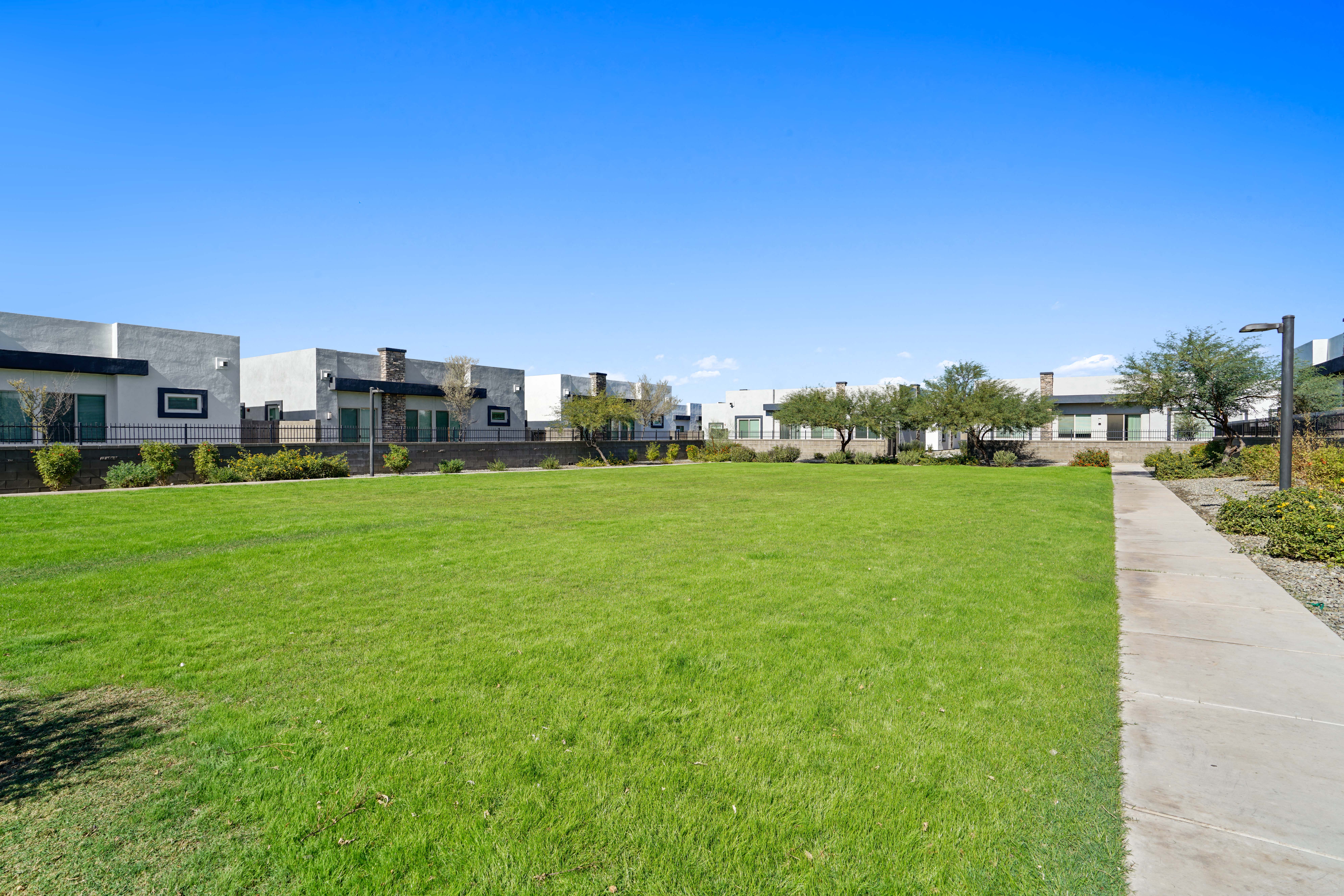 a green lawn in front of a row of apartment buildings at Olive Queen Creek Apartments, Queen Creek, 85142